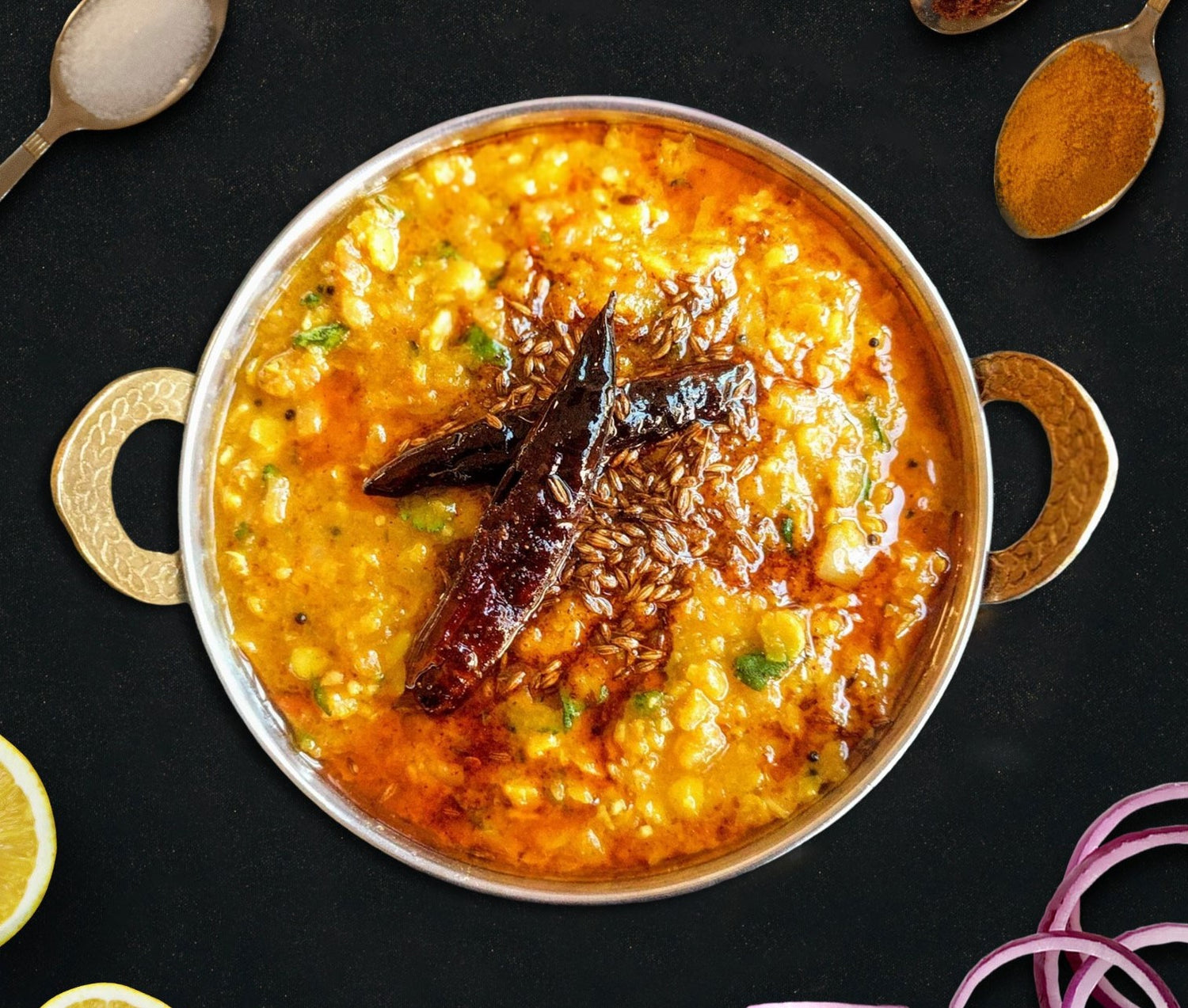  bowl of dal tadka with spices on a black background